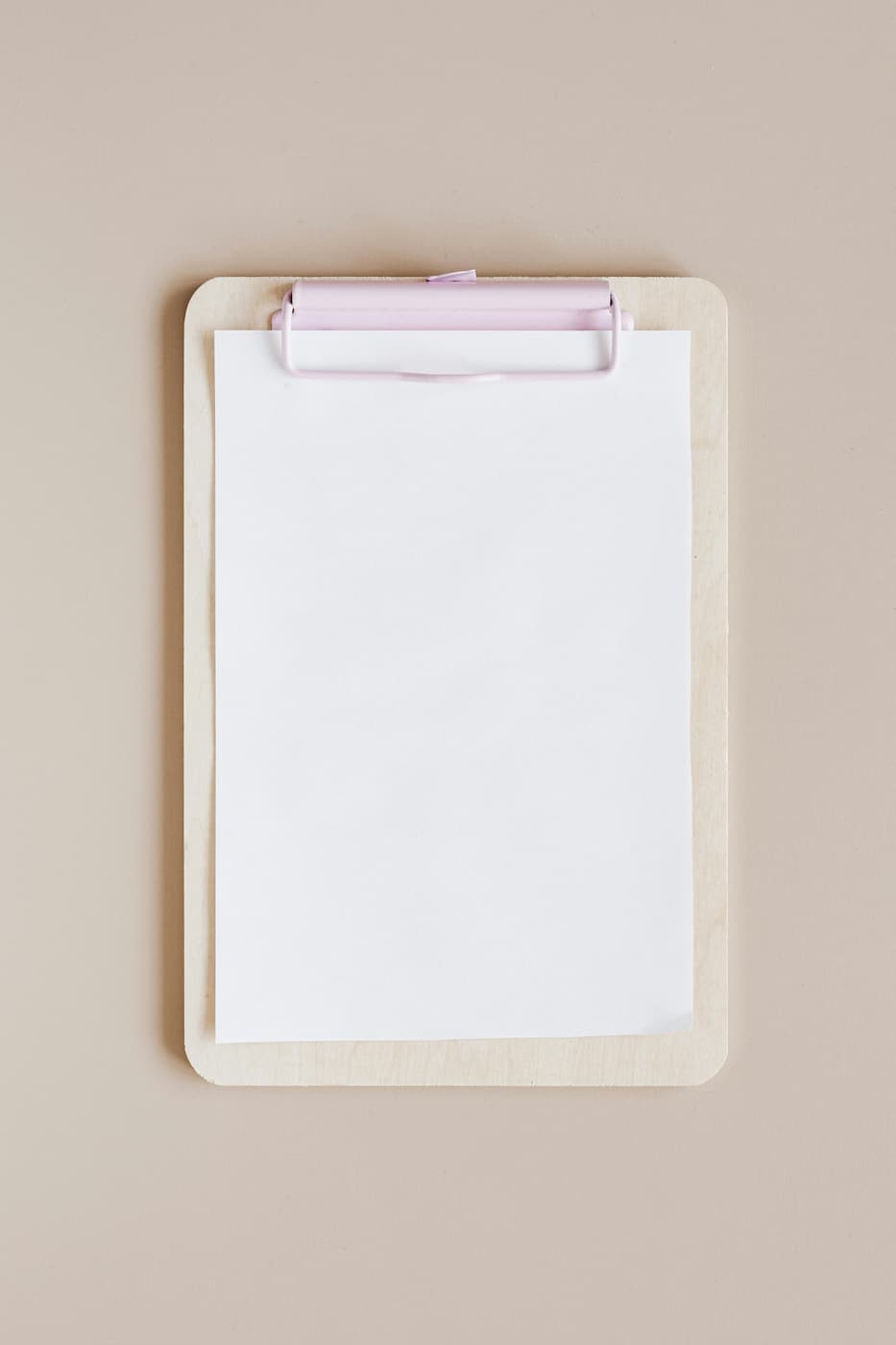 A blank clipboard is resting on a tan surface.